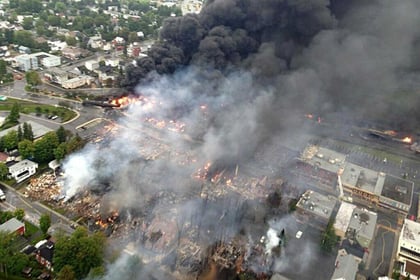 Photo: Huge clouds of thick black smoke were still rising from the centre of Lac-Megantic several hours after the disaster. (AFP: Surete du Quebec) 